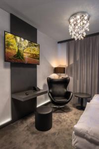 恰斯拉夫Hotel Grand的一间卧室配有一张床、一把椅子和一个吊灯。