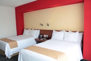 瓜达拉哈拉瓜达拉哈拉博览会智选假日酒店的红色墙壁的酒店客房内的两张床