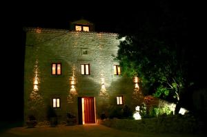 布尔戈斯Casa Rural Valle Esgueva的一座古老的石头建筑,晚上有红色的门