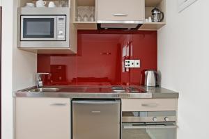 汉密尔顿阿斯特拉汽车旅馆的红色的厨房配有水槽和微波炉