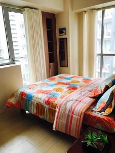 马尼拉Resorts World Condo的一间卧室配有一张带彩色毯子的床