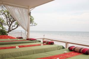 华欣华欣春景酒店的阳台设有三张床,背景为大海