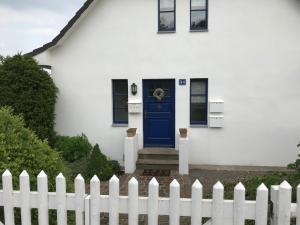 格洛韦Ferienwohnung Lilly的白色的房子,有蓝色的门和栅栏