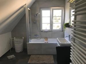 莱茵河畔威尔Ferienwohnung Haltingen的带浴缸、水槽和窗户的浴室