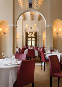 蓬特雷西纳Schloss Hotel & Spa Pontresina的用餐室配有白色的桌子和红色的椅子