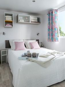 法克湖Strandcamping Gruber的卧室配有白色床和粉红色枕头
