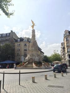 兰斯Hôtel des Arcades的街道中间的雕像,有建筑