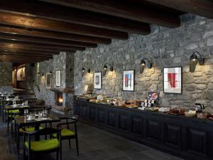 维蒂纳Art Mainalon Hotel的一间带桌椅和石墙的餐厅