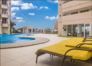 福塔莱萨Apartamento Praia do futuro Bech Village的一张黄色的床,坐在泳池旁的庭院