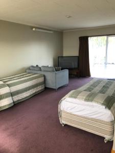 朗伊奥拉莉莉布鲁克汽车旅馆的一间卧室配有两张床、一张沙发和一台电视