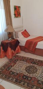比勒陀利亚科伦维德精品旅馆的一间卧室配有一张床和一张桌子,铺有地毯