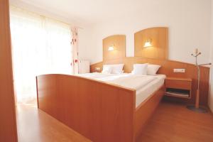 巴特法兴格豪斯黑尔德格德酒店的一间卧室配有一张大床和木制床头板