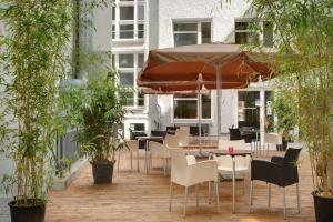 柏林柏林米特梅宁阁酒店的一个带桌椅和遮阳伞的庭院