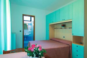 托尔托雷托Hotel Residence Margherita的一间卧室配有一张床和一张花瓶桌子