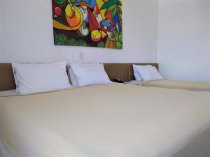 阿拉卡茹西马斯普拉亚酒店的卧室配有一张白色床,墙上挂有绘画作品
