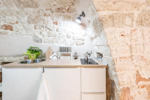 孔韦尔萨诺Da nonna Isabella的厨房配有白色橱柜和石墙