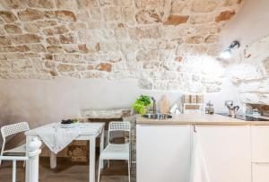 孔韦尔萨诺Da nonna Isabella的厨房配有白色橱柜和石墙