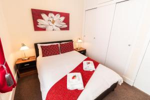 邓迪Mycosy Provost Road的卧室配有带红色枕头的白色床
