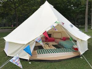 新加坡Glamping Kaki - Large Bell Tent的白色帐篷,在草地上配有一张床