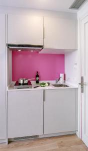 皮内达德马尔Bellsol Rooms的厨房配有白色橱柜和粉红色的墙壁