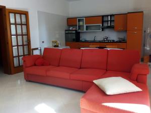 布林迪西Casa Paradiso的客厅里设有一张红色的沙发,配有厨房