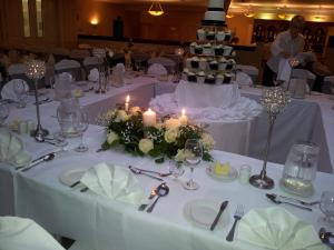 布拉尼布拉尼城堡酒店的一张桌子,桌子上摆放着带蜡烛的白色桌子,还有婚饼