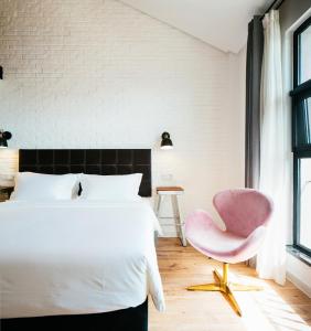 苏州欣得酒店留园虎丘店的卧室配有白色的床和粉红色的椅子