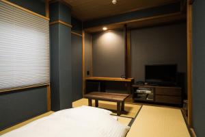 增田Hotel Daiei Masuda的一间卧室配有一张床、一张桌子和一台电视