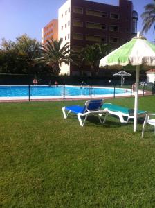 多列毛利诺斯Apartamentos La Roca Rentals的游泳池畔的2把躺椅和遮阳伞