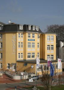 黑灵斯多夫Hotel See-Eck的前面有旗帜的大型黄色建筑