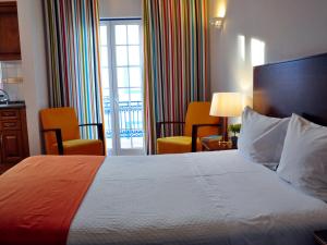 米尔芳提斯城Patios Da Vila Boutique Apartments by AC Hospitality Management的酒店客房,配有一张床和两把椅子