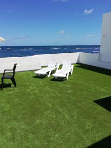 奥尔索拉Ocean Sunshine的一群坐在靠近海洋的草地上的白色椅子