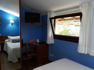 涅姆布罗托蓝达旅馆的卧室拥有蓝色的墙壁,设有窗户和床。