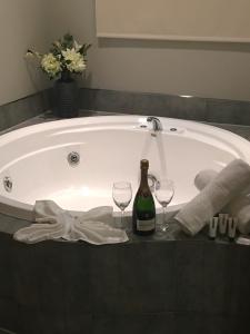 北哈夫洛克乡村汽车旅馆的浴缸配有1瓶葡萄酒和2杯葡萄酒