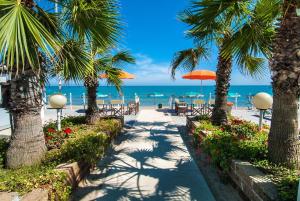 马帝斯兹罗Hotel Olimpic的一条拥有棕榈树和椅子的步道和海滩