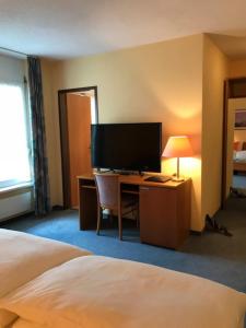 欧博比皮Hotel Eintracht的酒店客房配有一张床和一张书桌及一台电视