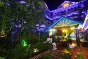芭东海滩Patong Sunbeach Mansion的一座建筑,设有棕榈树和灯的餐厅