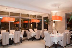 乌尔齐尼拉古纳酒店的一间设有白色桌椅和橙色灯光的餐厅