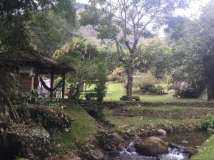 新弗里堡Sitio Recanto Lumiar的一座带溪流和小屋的花园
