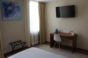 底拉斯卡拉Hotel Mirante Tlaxcala的卧室配有书桌和墙上的电视。
