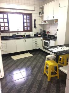 伊瓜苏Casa Da Tiete - Foz do Iguaçu - PR的厨房配有白色橱柜和黄色凳子