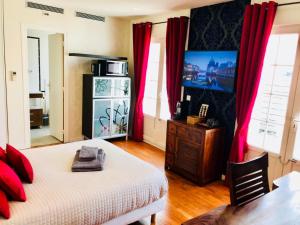 讷伊-普莱桑斯Villa Florian的一间卧室配有一张带红色窗帘的床和电视。