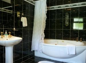 Ballymacarbry哈诺拉小屋旅馆及餐厅的黑色瓷砖浴室设有水槽和浴缸