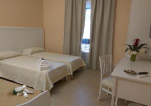吉诺萨滨海Le Camelie的酒店客房设有两张床和一张桌子。