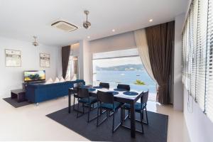 芭东海滩巴东吉娜拉别墅的一间带桌椅和大窗户的用餐室