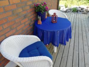 弗加尔巴卡Tallgatan Fjällbacka的一张带两把白色柳条椅的蓝色桌子和一张带鲜花的桌子