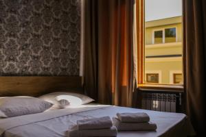 第比利斯Friendly Hotel的窗户旁的一张带毛巾的床