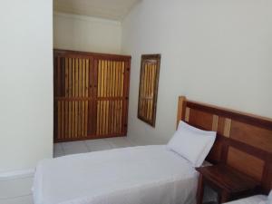 库尼亚Pousada Viajantes do Tempo的卧室配有白色的床和木制床头板