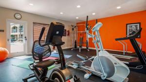 尤巴城尤巴贝斯特韦斯特城市酒店的一个带橙色墙壁的健身房和一个带健身自行车的房间