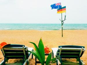 本托塔Sri Lancashire Guest House的海滩上两把椅子和一张带国旗的桌子